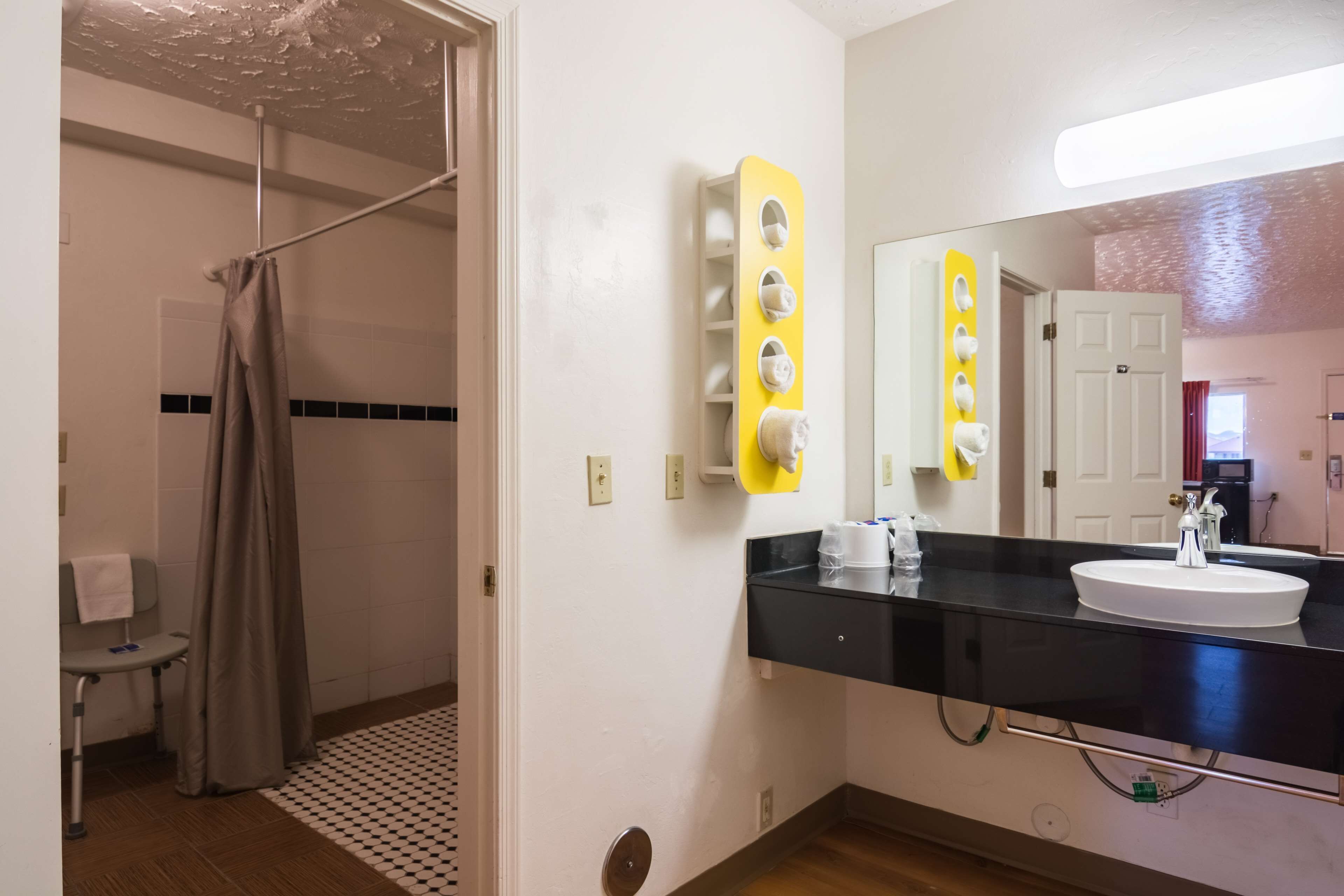 Un baño con lavamanos de encimera negro, un espejo y un perchero para toallas.