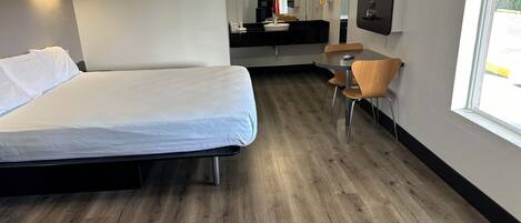 Habitació d'hotel amb llit, una petita taula i cadires, un lavabo i un mirall.