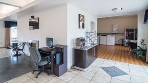A modern office space with a desk, computer, and office chair. There is a kitchenette with a microwave and coffee machine. The room has a large window and a ceiling light fixture. - Americas Best Value Inn Globe AZ (Globe)
