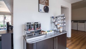 A coffee station with multiple espresso machines, a sugar dispenser, and a sign offering a morning charge-up for no charge. - Americas Best Value Inn Globe AZ (Globe)