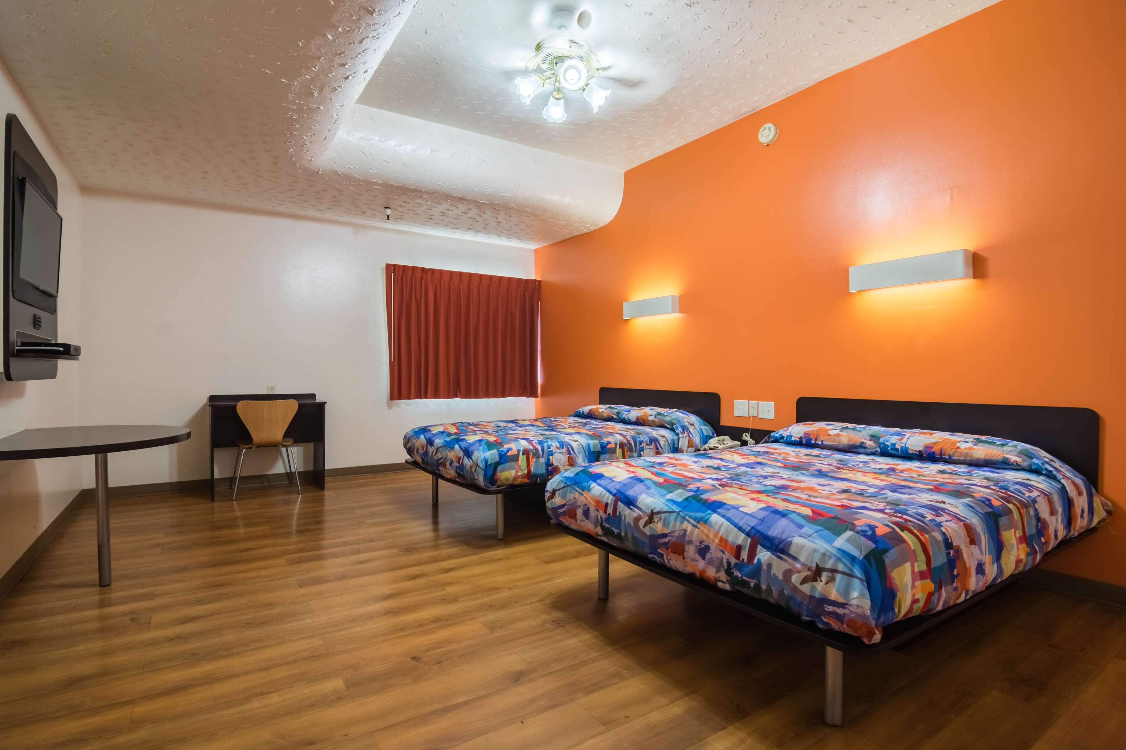 Una habitación con dos camas, un escritorio, una silla y un ventilador de techo.