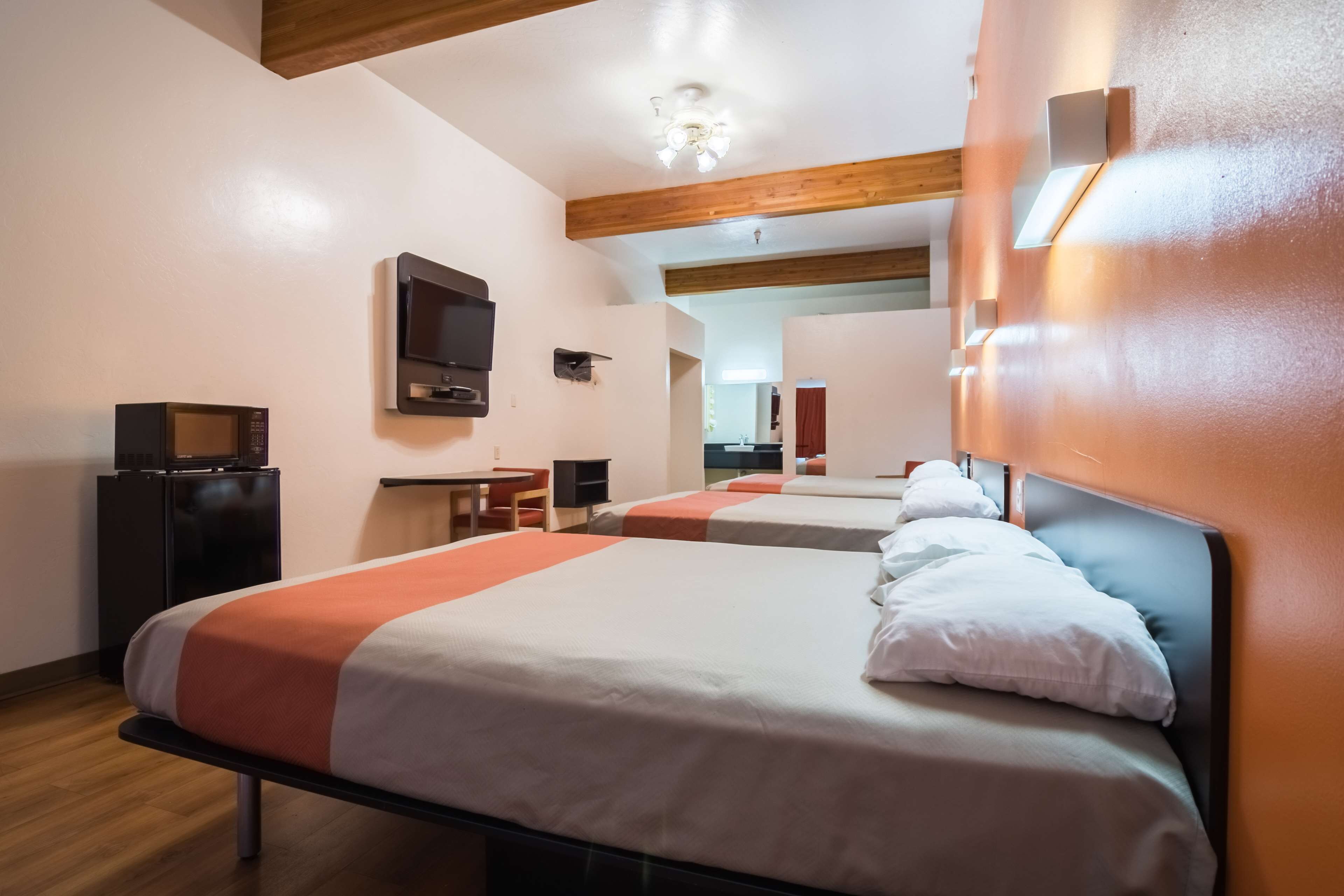 Una camera d'albergo con due letti, una scrivania, una televisione e uno specchio.