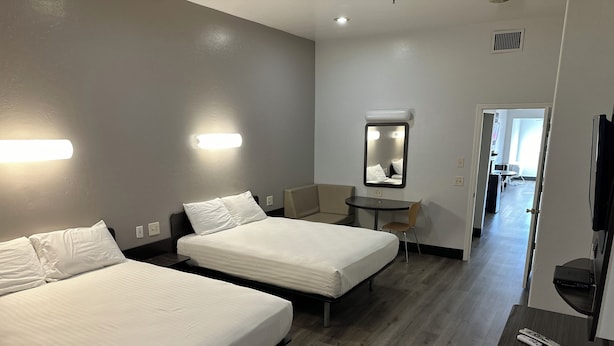 A hotel room with two beds, a small table, a chair, a TV, and a mirror. - Americas Best Value Inn Globe AZ (Globe)