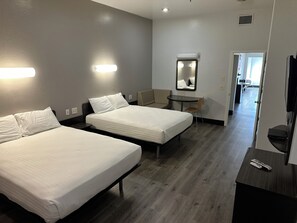 A hotel room with two beds, a small table, a chair, a TV, and a mirror. - Americas Best Value Inn Globe AZ (Globe)