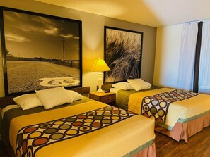 A hotel room with two beds, a nightstand, a lamp, and two large framed pictures on the walls. - Super 8 by Wyndham Dodge City (Dodge City)