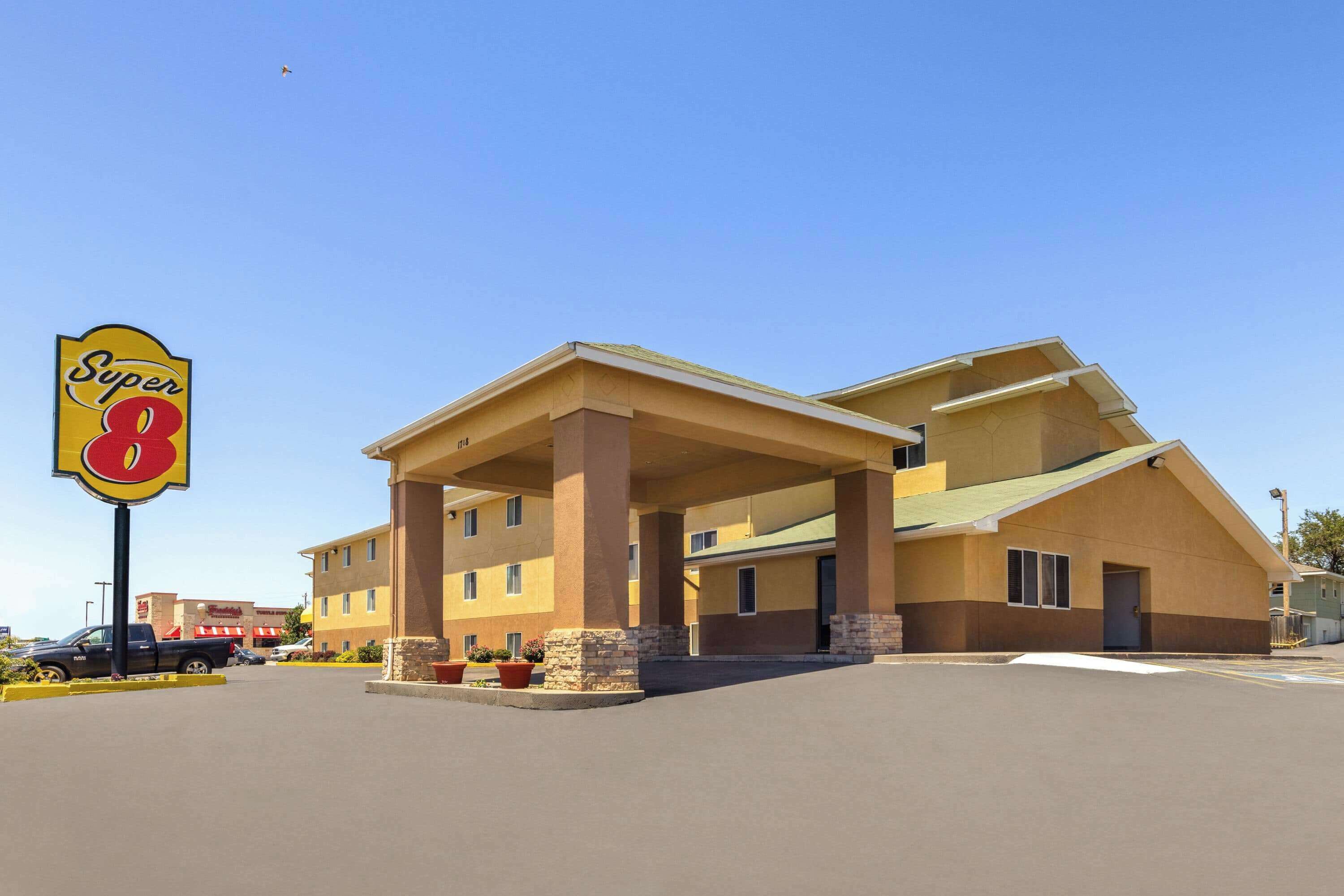 A Super 8 hotel with a covered parking area and a clear blue sky.