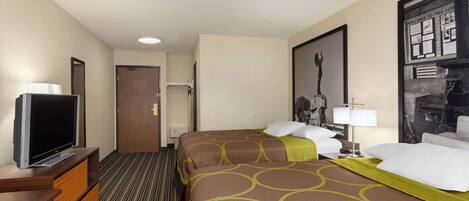 Habitación de hotel con televisor sobre un soporte de madera, una cama con colcha estampada y un cuadro en la pared.