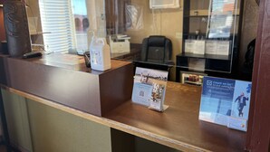 A reception desk with a hand sanitizer dispenser, a phone, and informational posters. - Super 8 by Wyndham Dodge City (Dodge City)