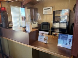 Mostrador de recepción con dispensador de gel hidroalcohólico, teléfono y carteles informativos.