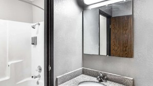 A bathroom with a white bathtub, a granite sink, and a mirror with a wooden frame.