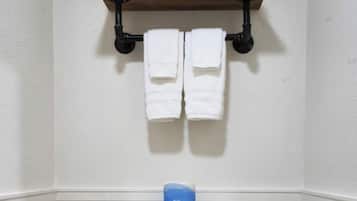 A bathroom with a white toilet, a shelf with towels, and a blue tissue box.