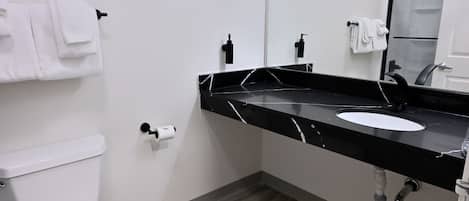A modern bathroom with a white toilet, black marble sink, and a mirror.