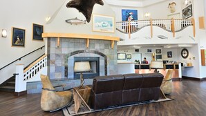 A spacious lobby with a stone fireplace, leather seating, and a reception desk.