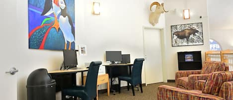 A conference room with two desks, chairs, a trash bin, and a large painting of puffins.