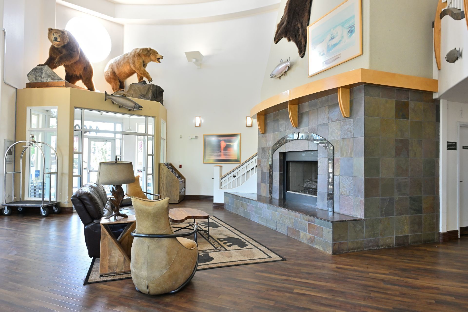 A lobby with a fireplace, wooden flooring, a reception desk, and bear taxidermy.