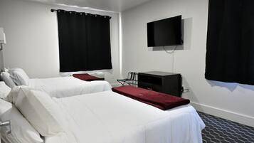 Habitación de hotel con dos camas, un televisor y un escritorio.