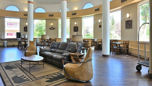 A spacious lobby with a leather sofa, a round table, and a unique chair. Large windows provide natural light and views of the outdoors.