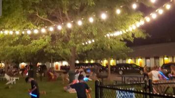 A nighttime outdoor area with string lights, a fenced area, and people.