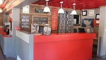 A reception area with a red counter, pendant lights, and various signs including one that says "Shoot the Moon Among the Stars."