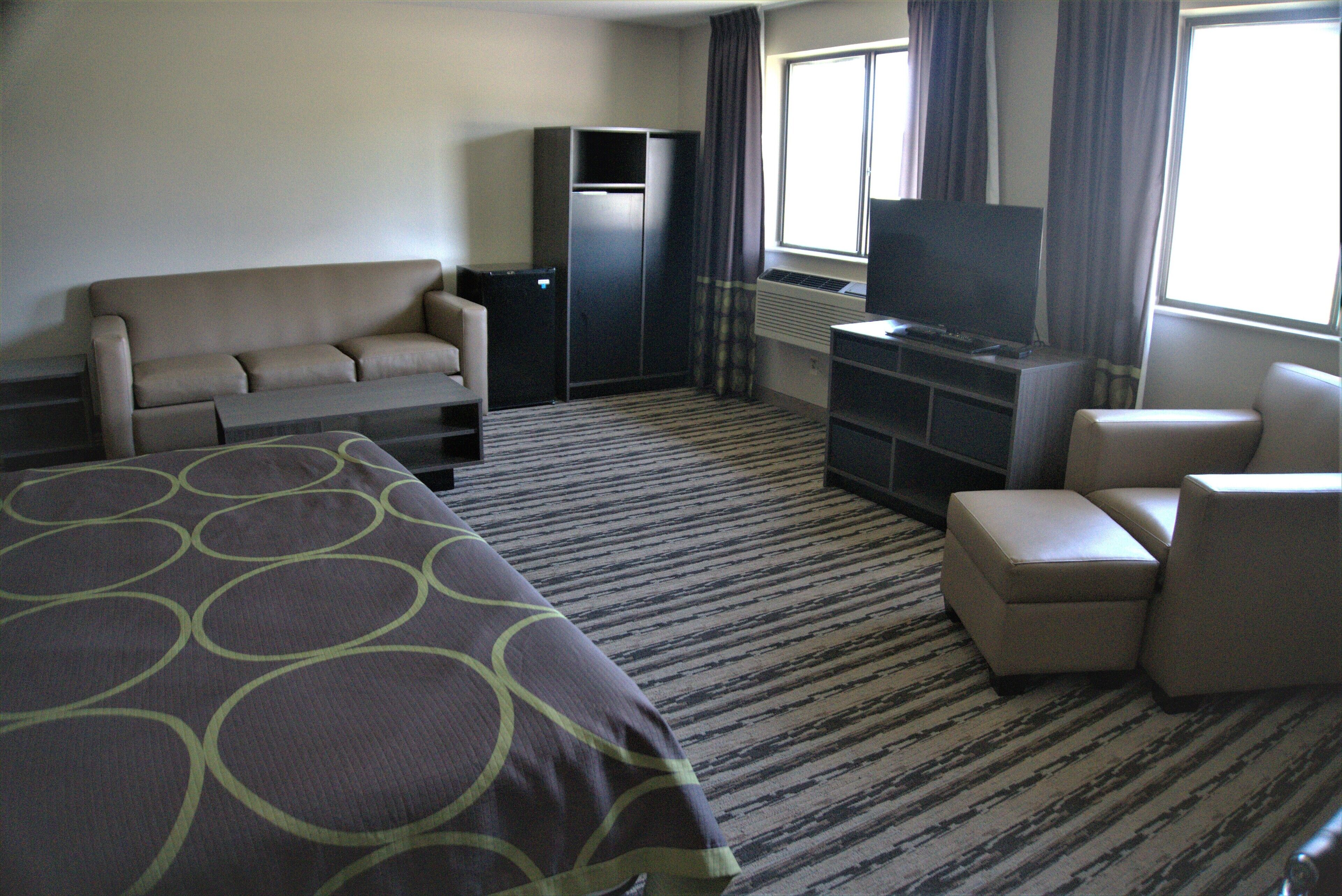 Una habitación de hotel con una cama grande, un sofá, un televisor, un escritorio y una silla.