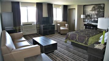 Habitación de hotel con cama, escritorio, silla, televisor y aire acondicionado.