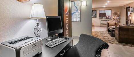 Een hotelkamer met een bureau, printer, lamp en een comfortabele stoel.