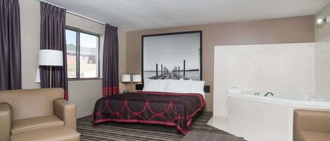 Habitación de hotel con cama, sofá, escritorio, bañera y una ventana grande con cortinas.