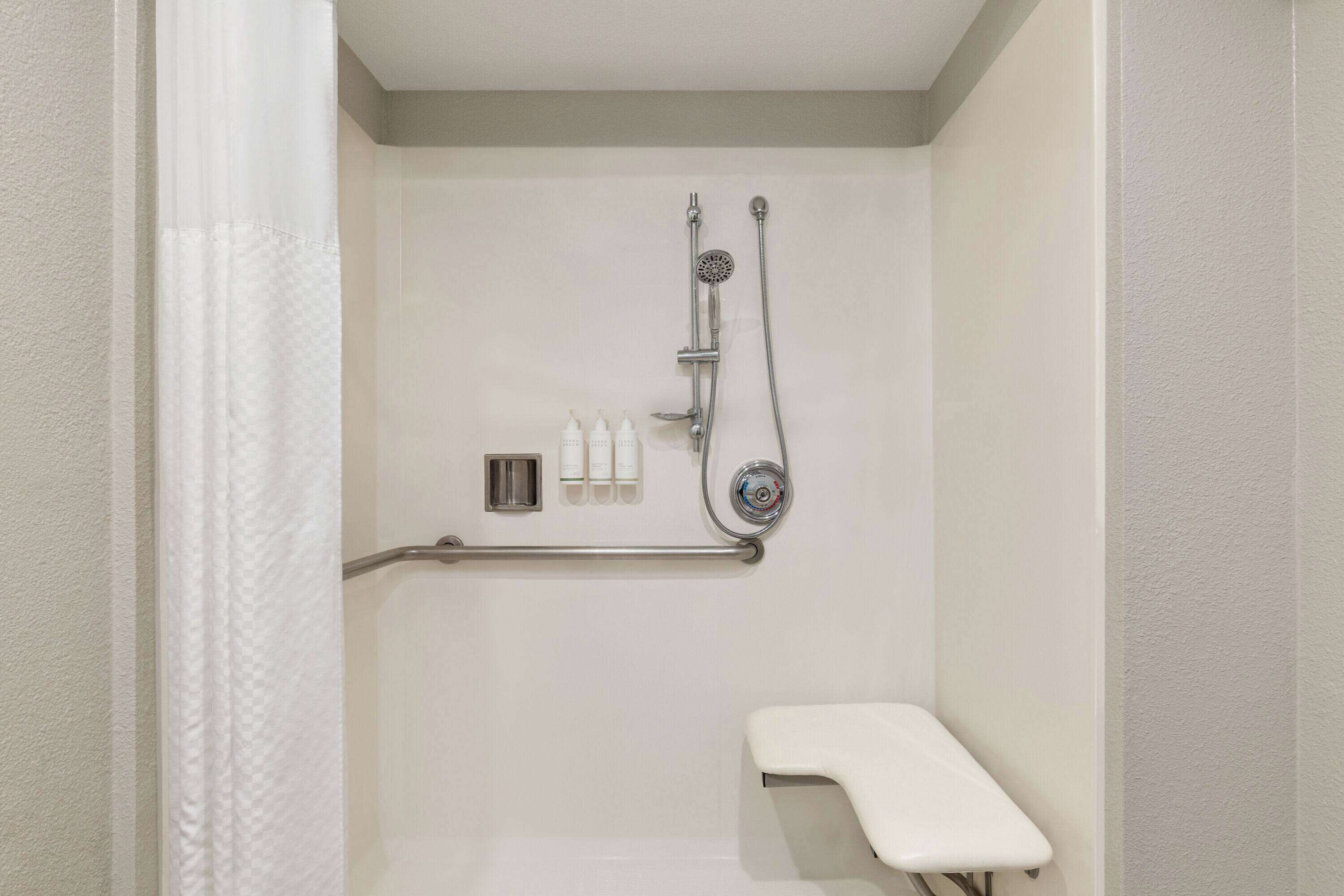 Une salle de bain équipée d’une douche, d’une barre d’appui et d’un banc.