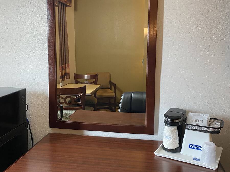 Una habitación de hotel con un escritorio de madera, una cafetera y una bandeja con un sobre de café.