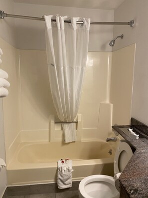 A bathroom with a bathtub, toilet, and a shower curtain. - Travelodge by Wyndham La Porte/Michigan City Area (La Porte)