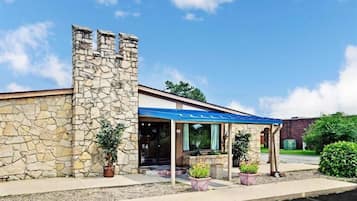 Un edificio de piedra con un toldo azul, un acceso cubierto y plantas en macetas.