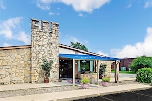 A stone building with a blue awning, a covered entrance, and potted plants. - Knights Inn Indianapolis South (Indianapolis)