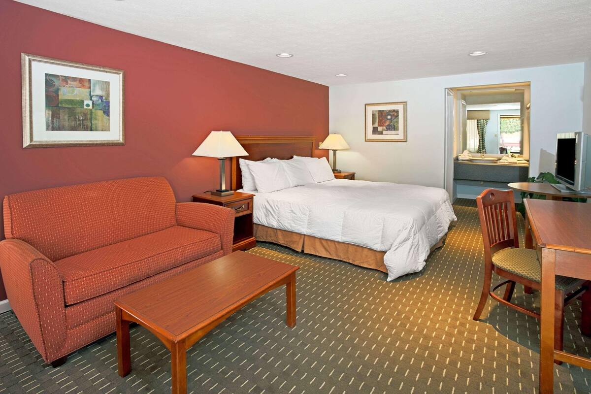 A hotel room with a bed, a sofa, a table, and a TV.
