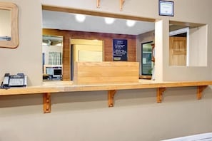 A reception desk with a wooden counter, a telephone, and a signboard. - Knights Inn Indianapolis South (Indianapolis)