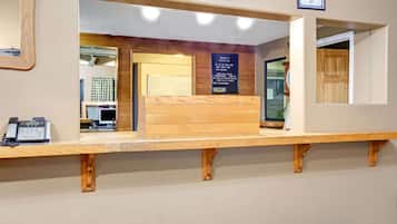 Una recepción con mostrador de madera, un teléfono y un cartel con información del hotel.