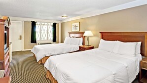 A hotel room with two beds, a desk, a lamp, and a window with curtains. - Knights Inn Indianapolis South (Indianapolis)