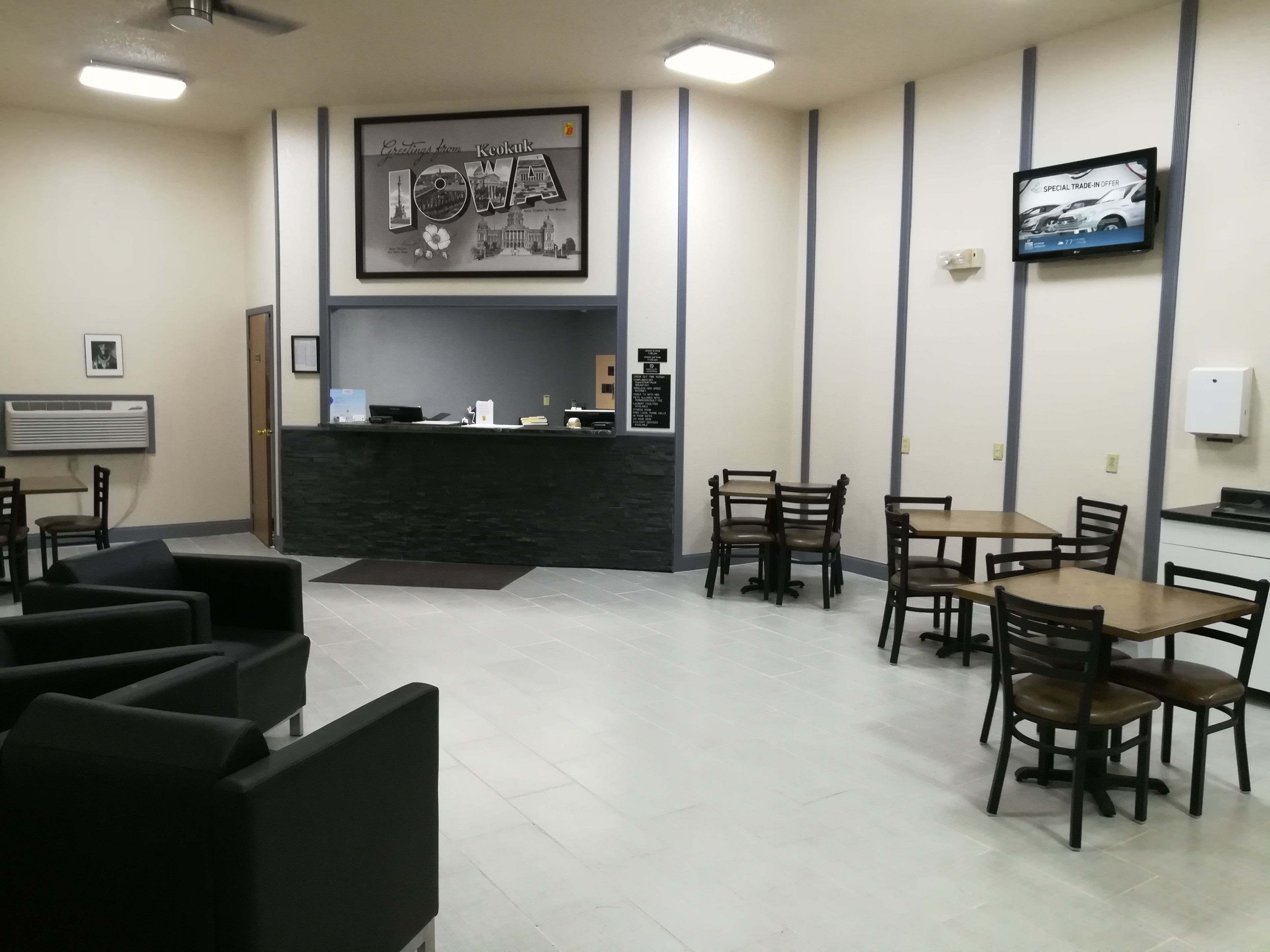 A reception area with a counter, chairs, tables, and a framed welcome sign.