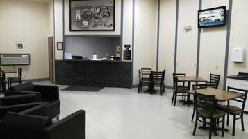 A reception area with a counter, chairs, tables, and a framed welcome sign.