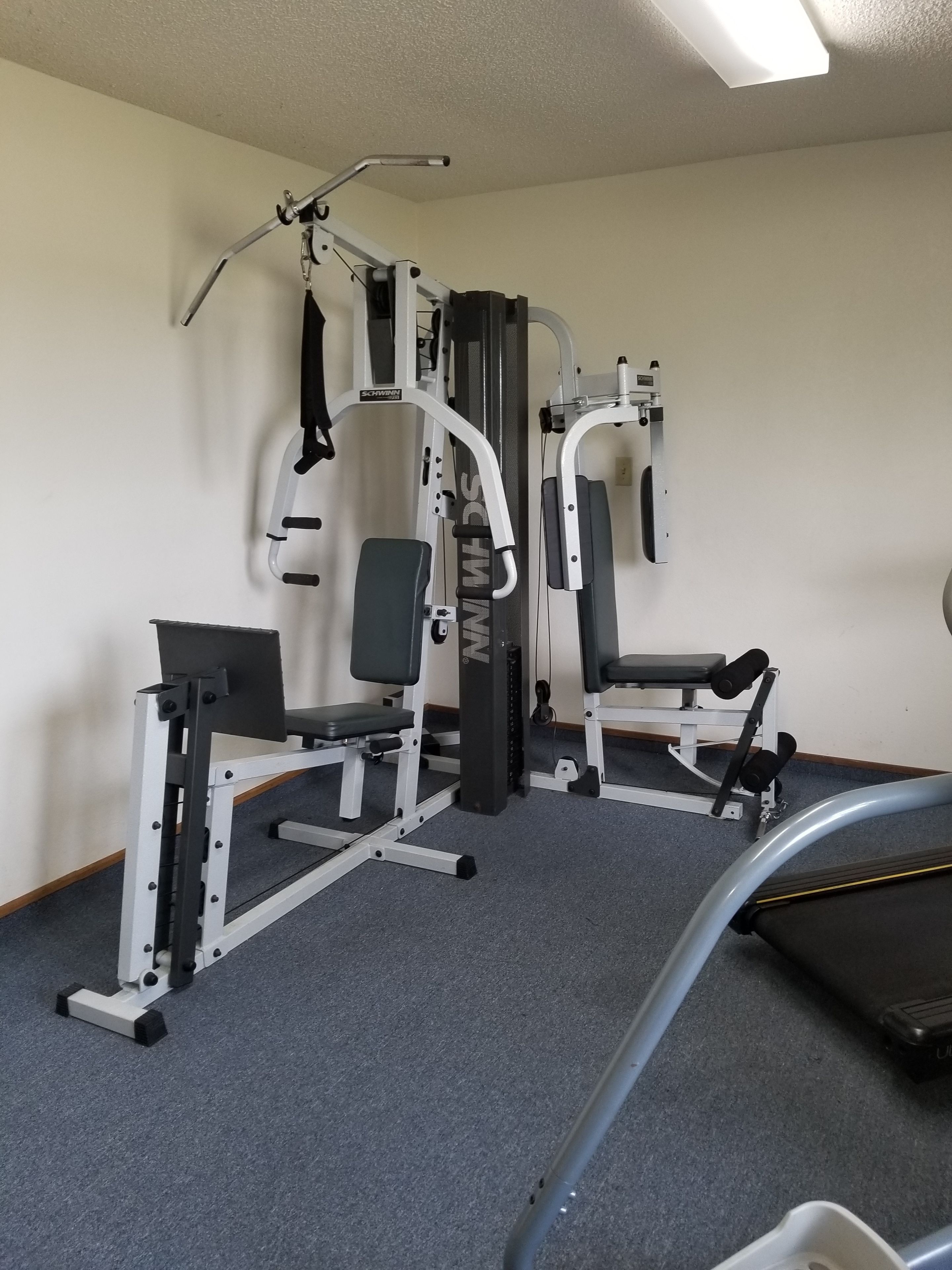 A gym with weight machines, benches, and a treadmill.