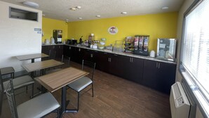 A breakfast area with a counter, seating, and a vending machine. - Super 8 by Wyndham Keokuk (Keokuk)
