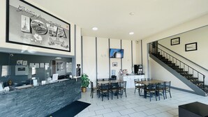 A hotel lobby with a reception desk, seating area, staircase, and a framed welcome sign. - Super 8 by Wyndham Keokuk (Keokuk)
