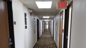 A hotel corridor with patterned carpet, doors on both sides, and an EXIT sign above the right door. - Super 8 by Wyndham Keokuk (Keokuk)