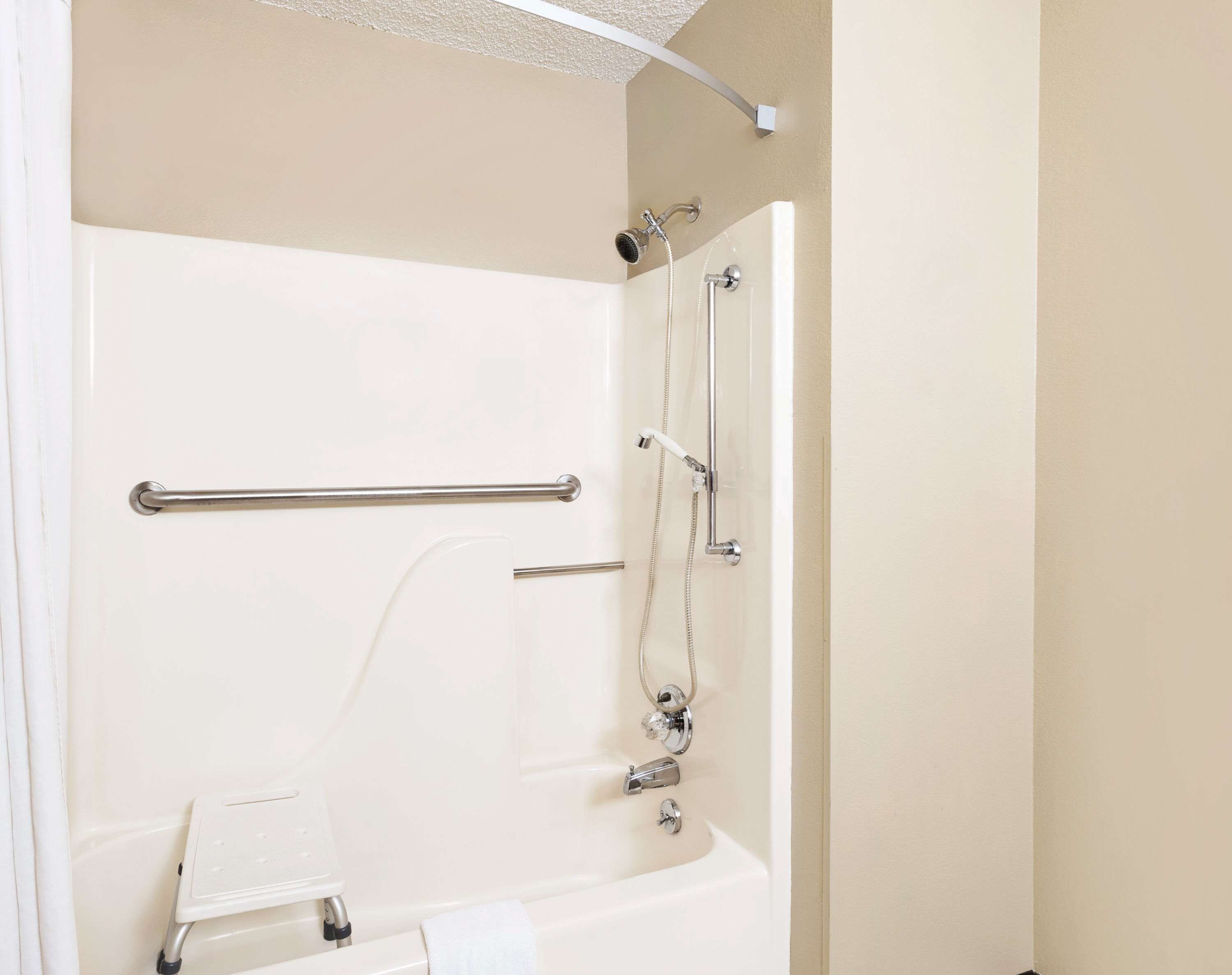 Un baño con bañera, ducha y barra de apoyo.
