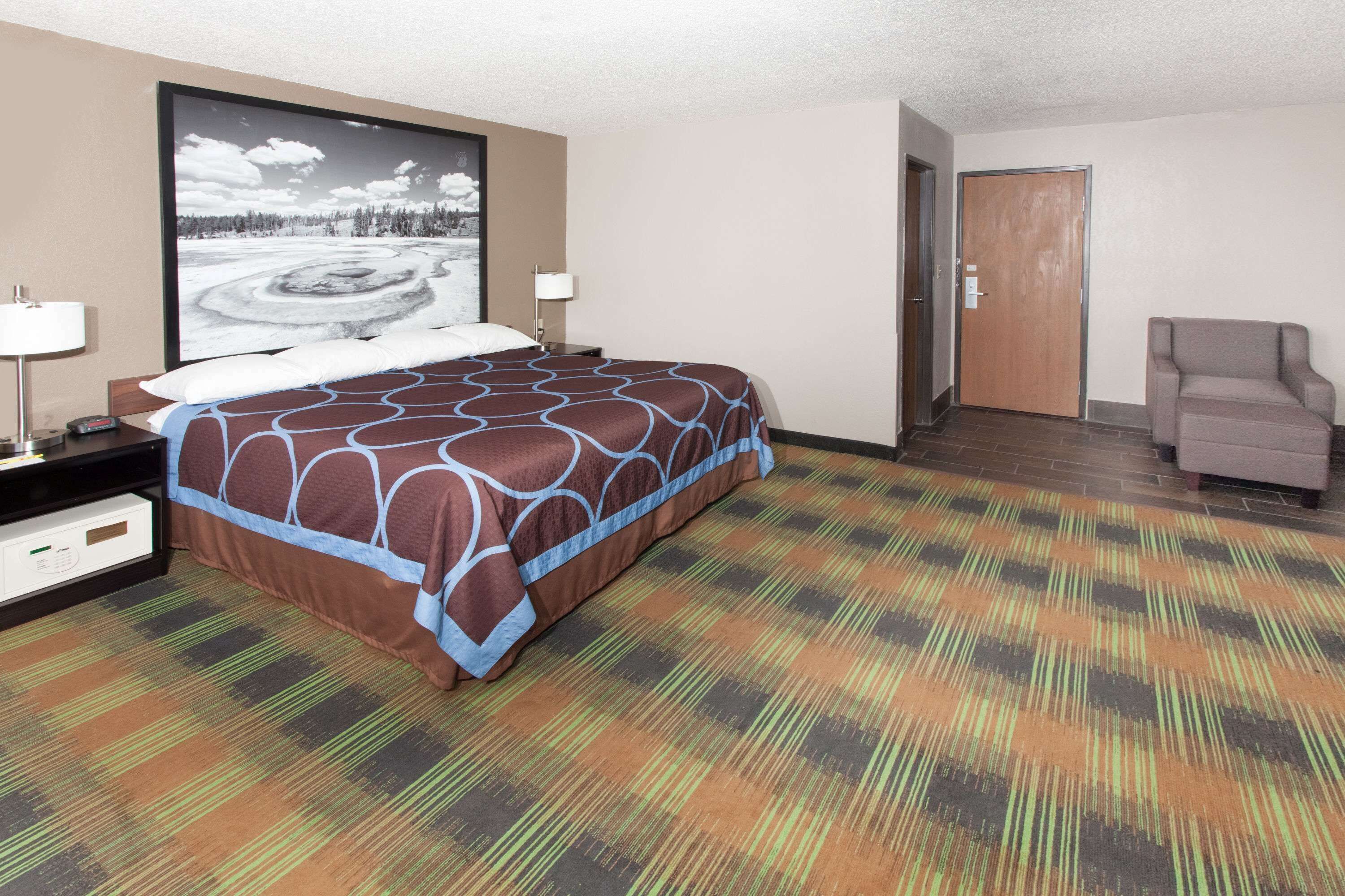 Una habitación de hotel con una cama grande, una silla, un escritorio y un televisor en la pared.