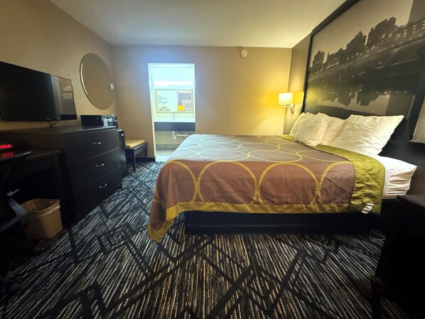 A hotel room with a bed, a desk, a chair, a television, and a window. - Super 8 by Wyndham Lakeland (Arlington)