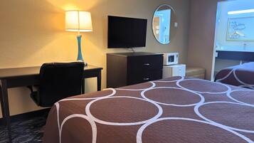 Habitación de hotel con cama, escritorio, silla, televisión, espejo y microondas.