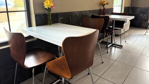 A restaurant interior with a white table, brown chairs, and two vases with yellow flowers.