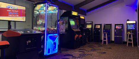 Un espacio de juegos con máquinas de arcade, un gran juego de la Lotería Cohete, y un letrero que indica el costo por jugar.