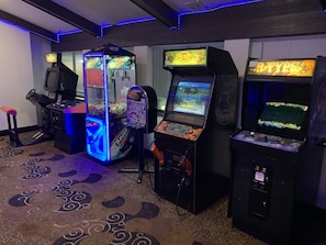 Un espace de jeux avec des bornes d’arcade, notamment un jeu de tir à récompenses et un jeu de type « teste tes réflexes ».