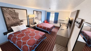 Ein Hotelzimmer mit zwei Betten, einem Schreibtisch, einem Stuhl, einem Spiegel und Bildern an den Wänden.